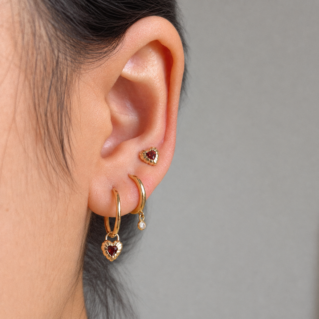 Fearless Heart solid-gold stacked earrings worn on the ear, clean neutral background